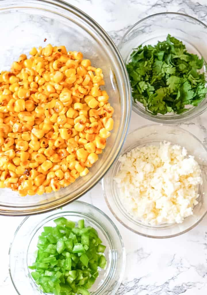 elote dip ingredients including corn, cilantro, Mexican cheese and jalapeno
