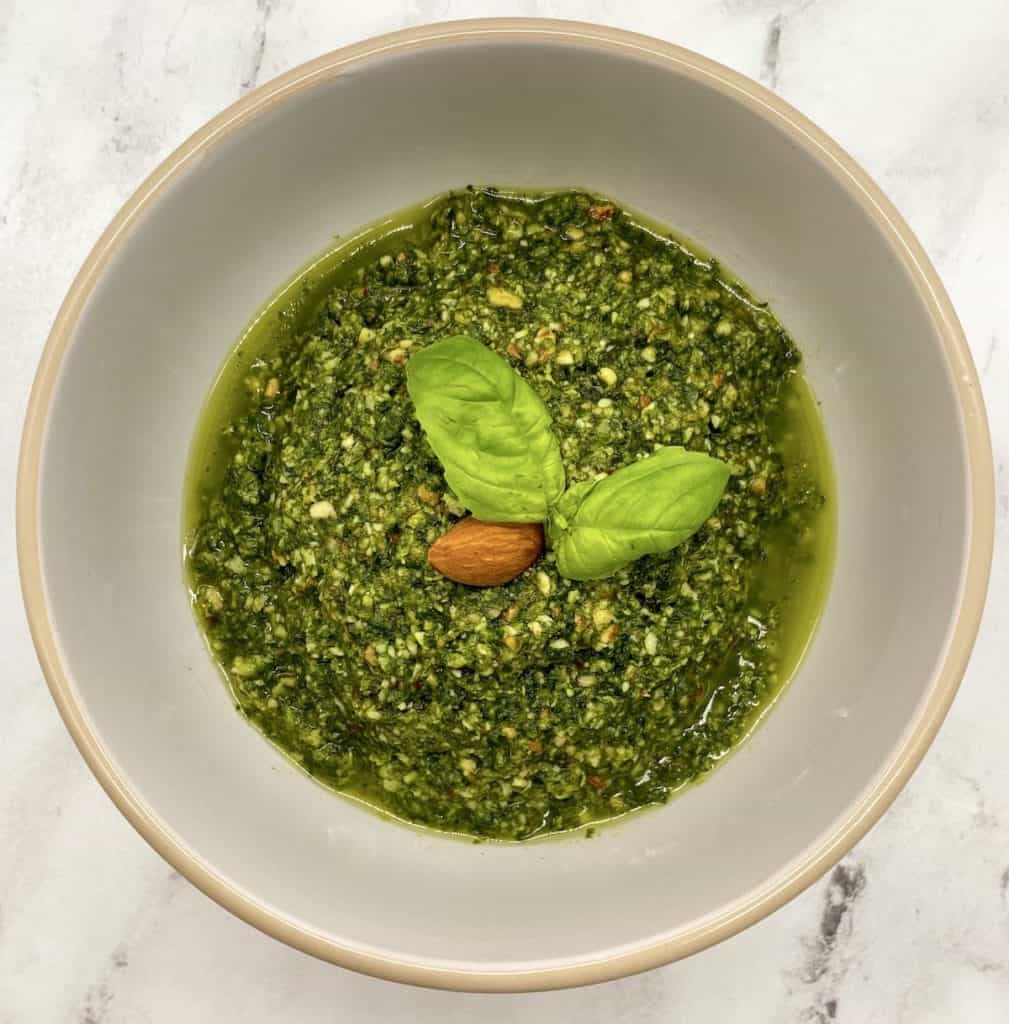 almond pesto dip in a bowl with almond and basil garnish