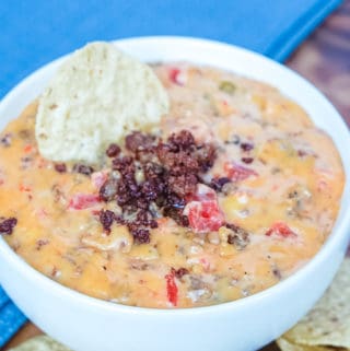 prepared rotel dip with cooked sausage and a tortilla chip garnish