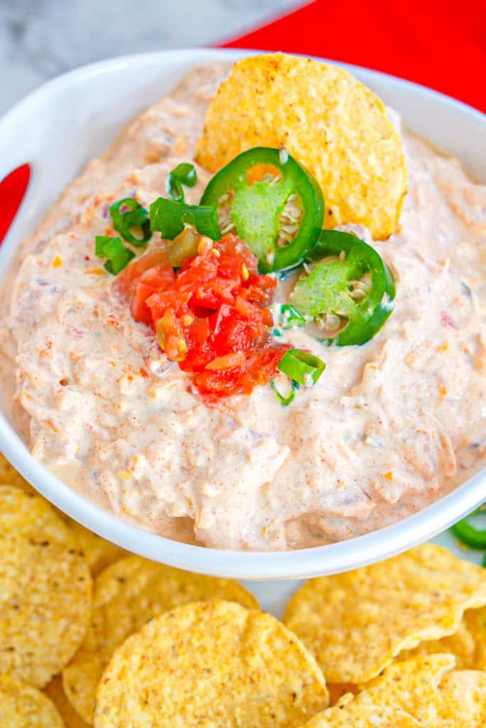 4 ingredient taco dip ion a white bowl with Mexican garnishes