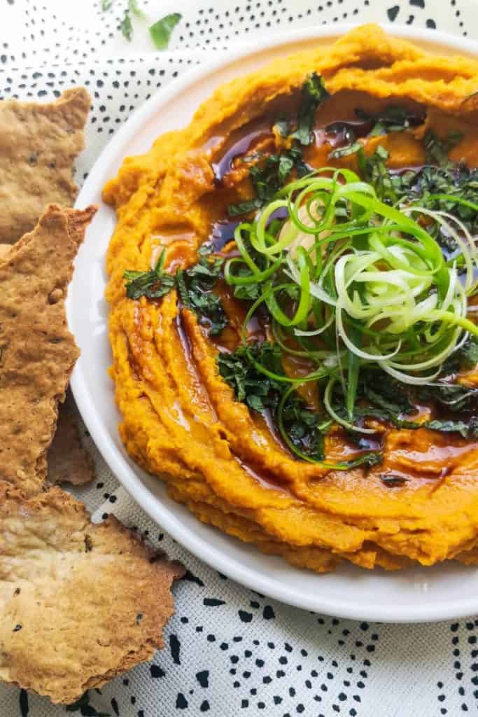 spice roasted carrot dip on a dish with vegan crackers