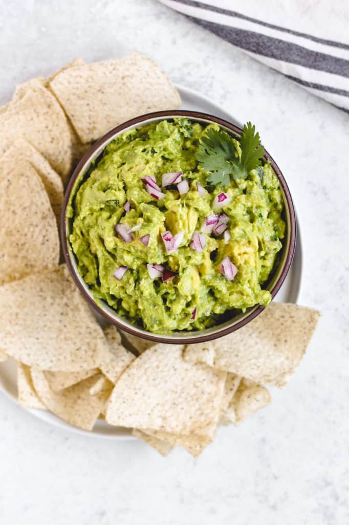 prepared fresh guacamole in a bowl surrounded by tortilla chips