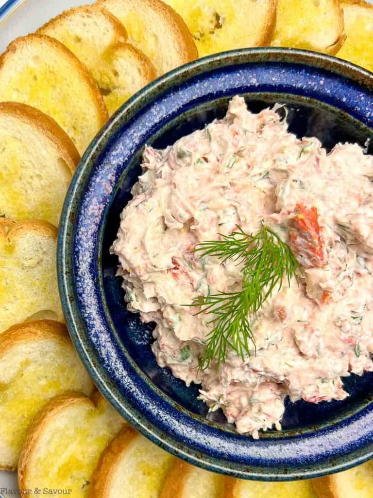 smoked salmon dip in a blue dish with toasted bread on the side for dipping