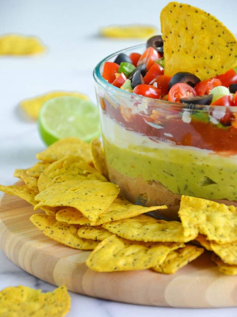 prepared vegan seven layer dip with tortilla chips on the side