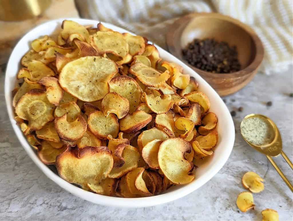 baked parsnip chips in a large white bowl