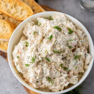 overhead photo of salmon cream cheese dip with dill garnish and sliced baguette on the side