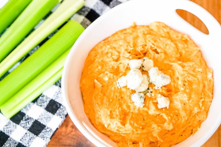 buffalo chicken dip in a white serving bowl with celery on the side