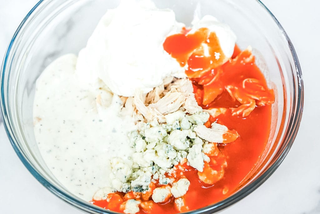Franks Red Hot Buffalo Chicken Dip ingredients in a clear mixing bowl.
