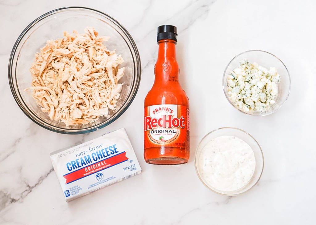 shredded chicken, cream cheese, franks red hot sauce, blue cheese crumbles and ranch dressing on a marble counter