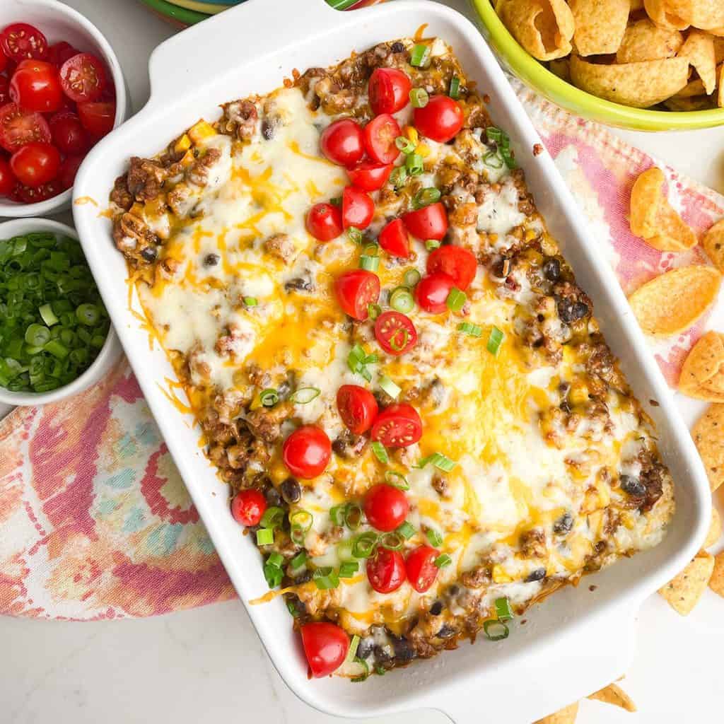 overhead photo of taco dip with ground beef in a white casserole dish 
