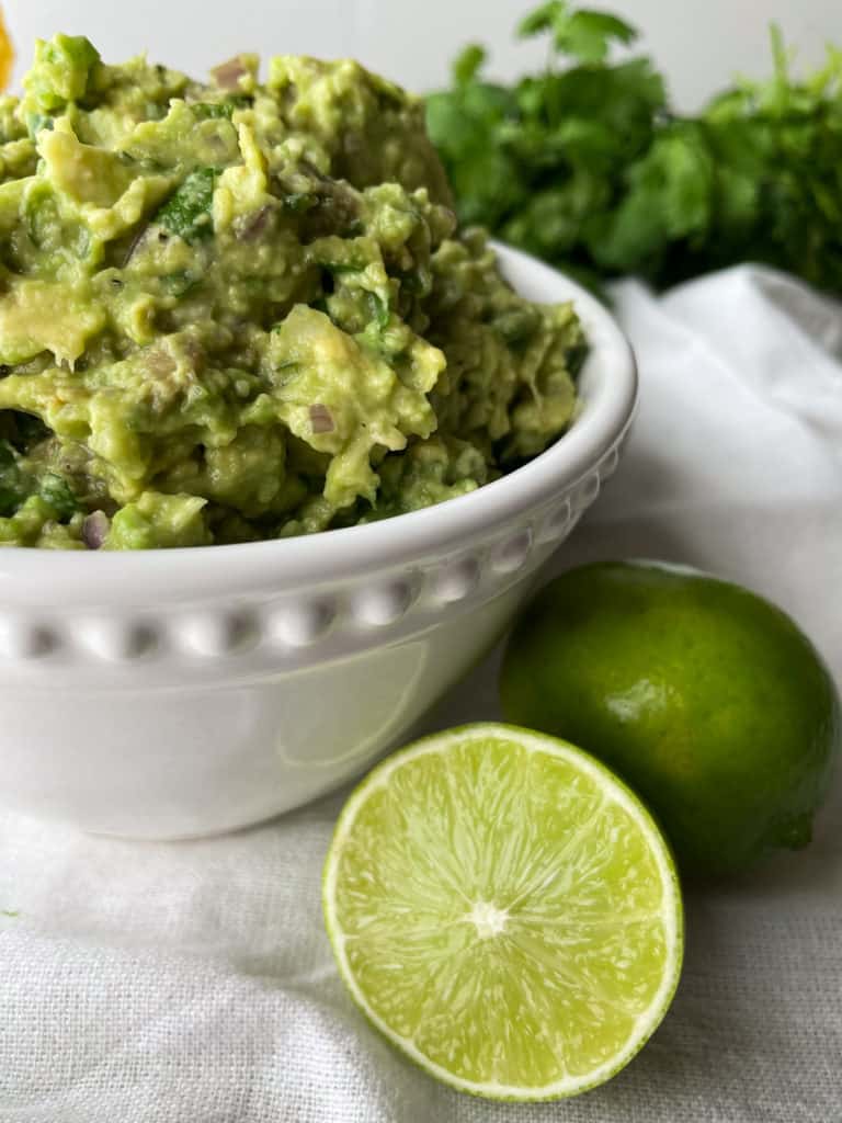 a white bowl filled with tomato free guacamole