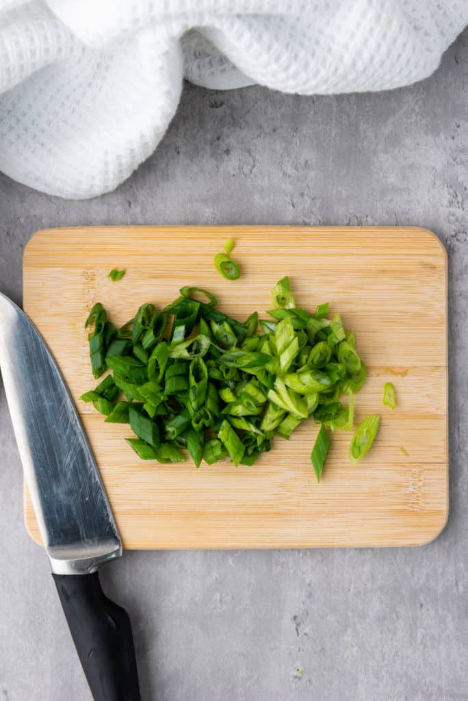 sliced chives on a wooden cutting board+