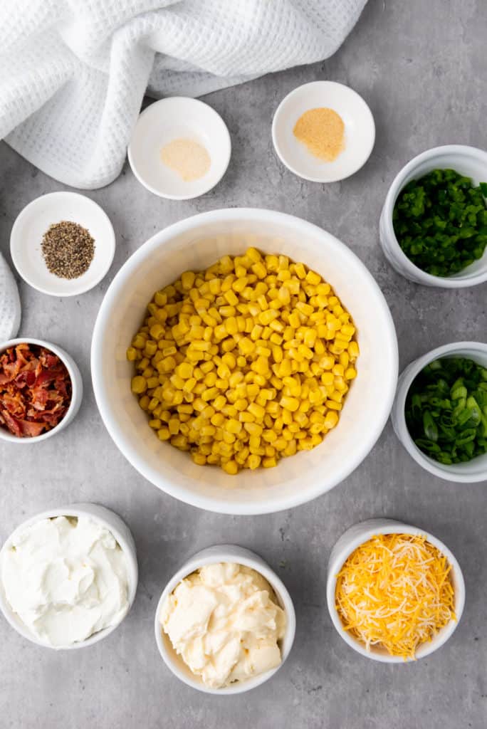corn dip recipe ingredient including corn kernals, bacon, chives, cheese and spices.