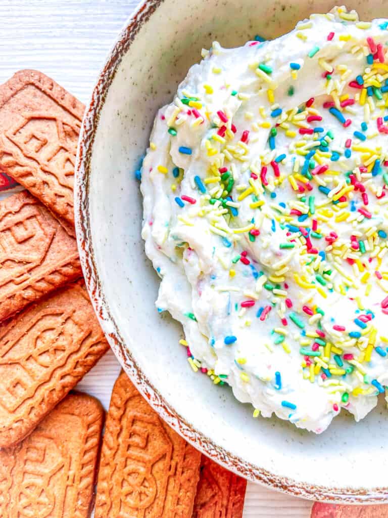 up close photo of funfetti dip with sprinkles and cookies on the side