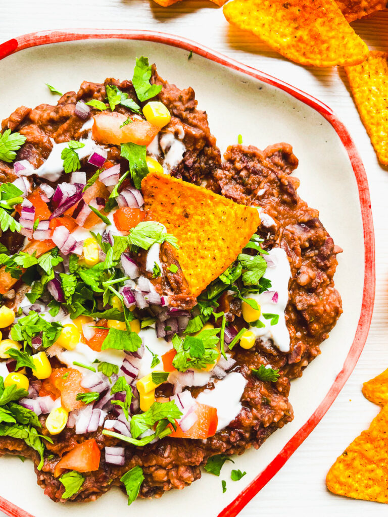 black bean dip loaded with tomatoes, onion, sour cream served with Doritos tortilla chips