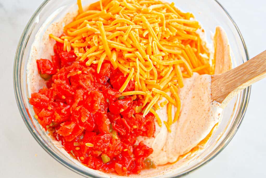 Overhead shot of sour cream taco seasoning mixture with Rotel tomatoes and shredded cheddar cheese