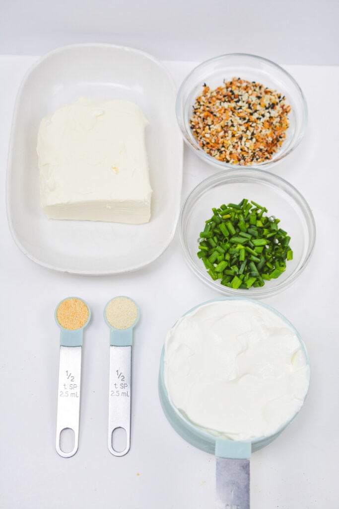 Overhead shot of everything bagel dip ingredients in individual containers on table