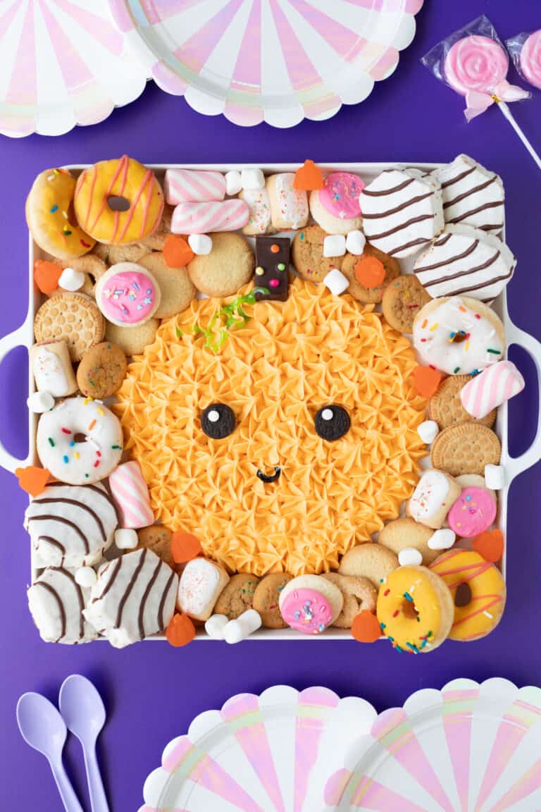 complete halloween pumpkin frosting board surrounded by cookies and cakes on a purple background
