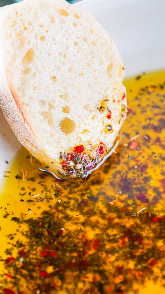 bread slice being dipped in oil with spices 