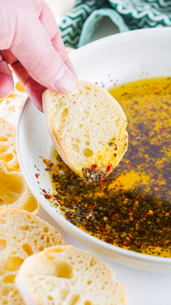 baguette slice being dipped in homemade bread dipping oil