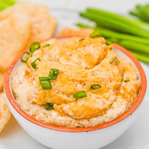 prepared warm crab rangoon dip in a bowl garnished with green onions