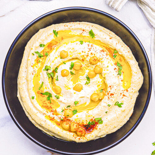 authentic hummus recipe made with chickpeas tahini, olive oil and spices, prepared in a black bowl