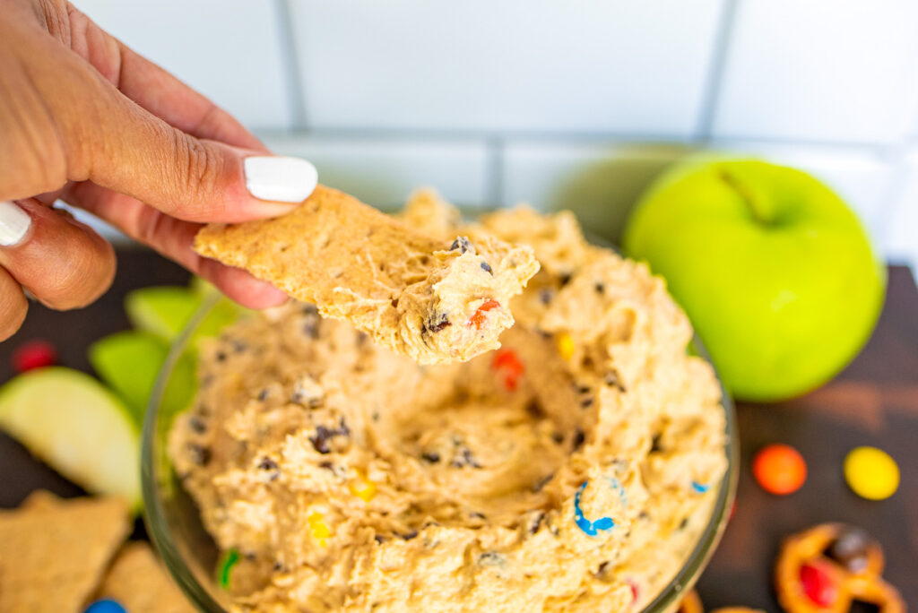 graham cracker being dipped into monster cookie dough dip