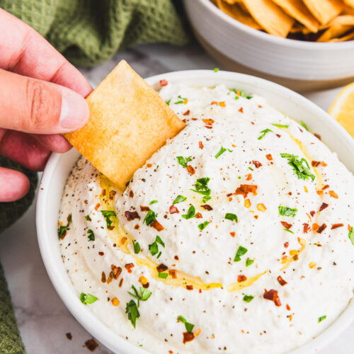 a pita chip being dipped into whipped feta