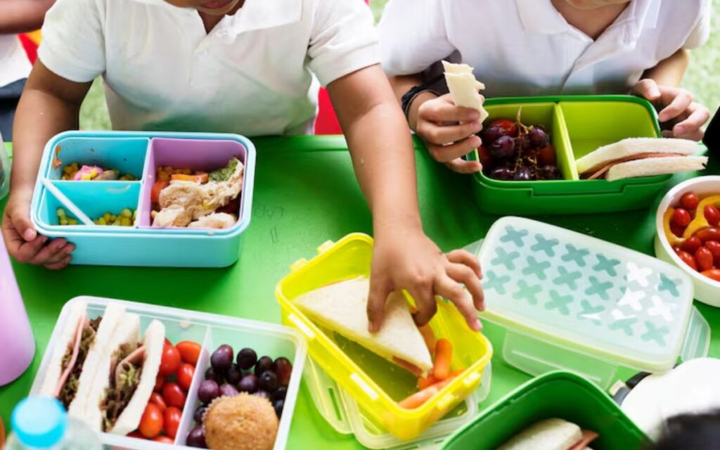 Kids with lunchboxes at a cafeteria table