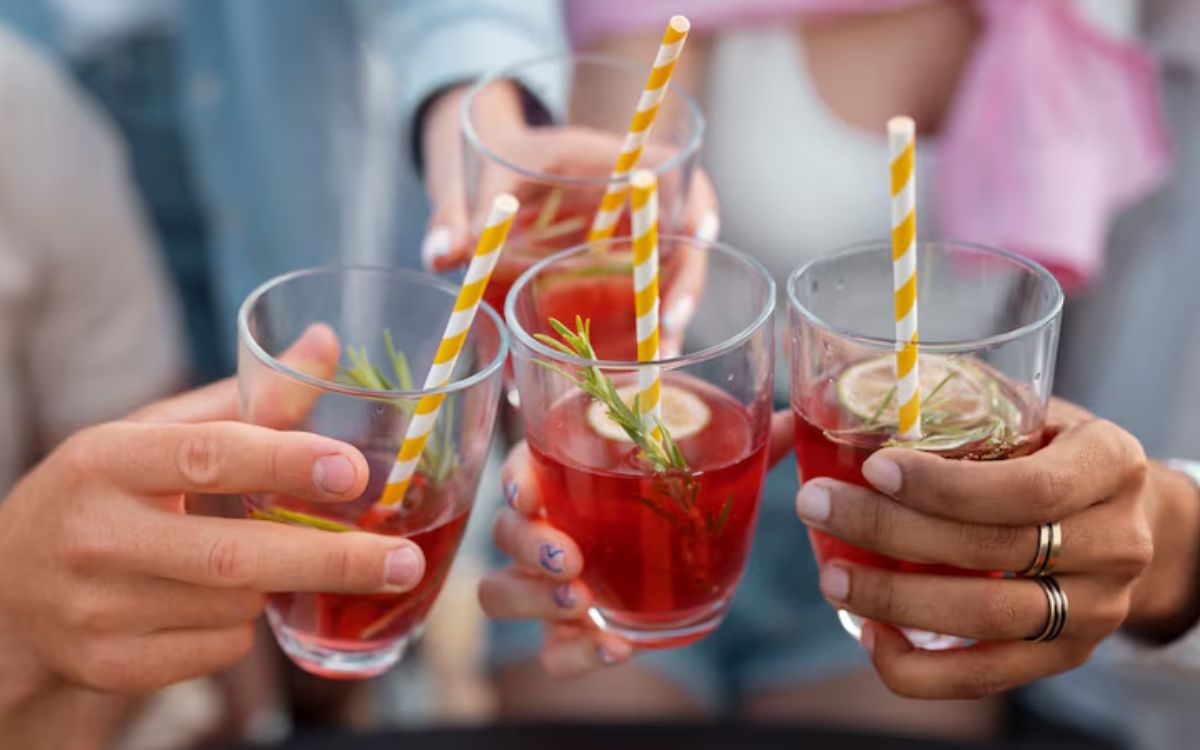 Friends toasting red cocktails with striped straws