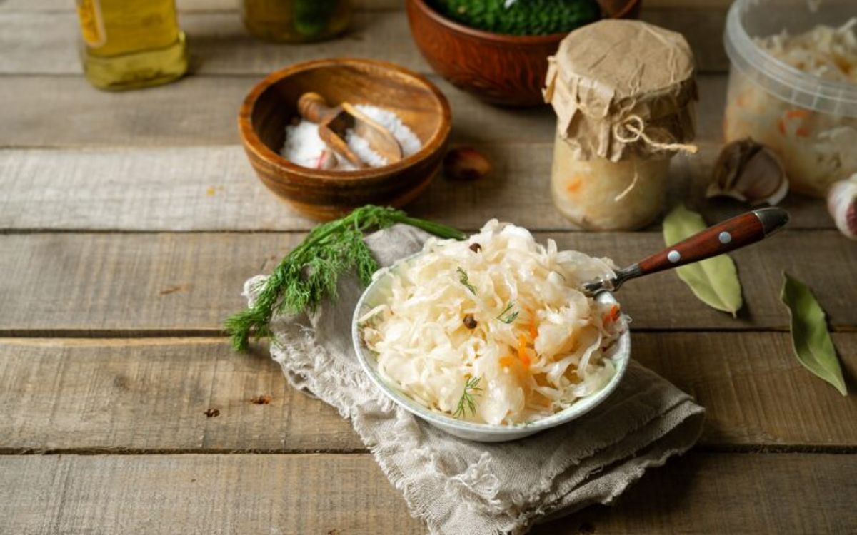 Bowl of sauerkraut with spices and herbs on a rustic table