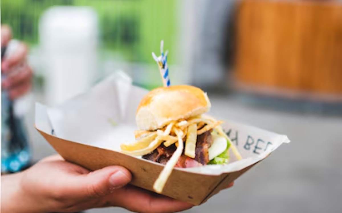 Mini burger topped with fries in a cardboard tray