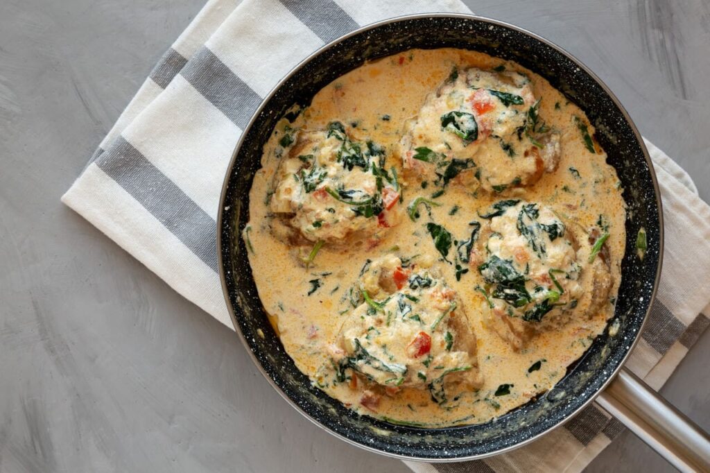 Homemade Creamy Tuscan Chicken with Spinach in a Pan, top view. From above, overhead, flat lay. copyspace.