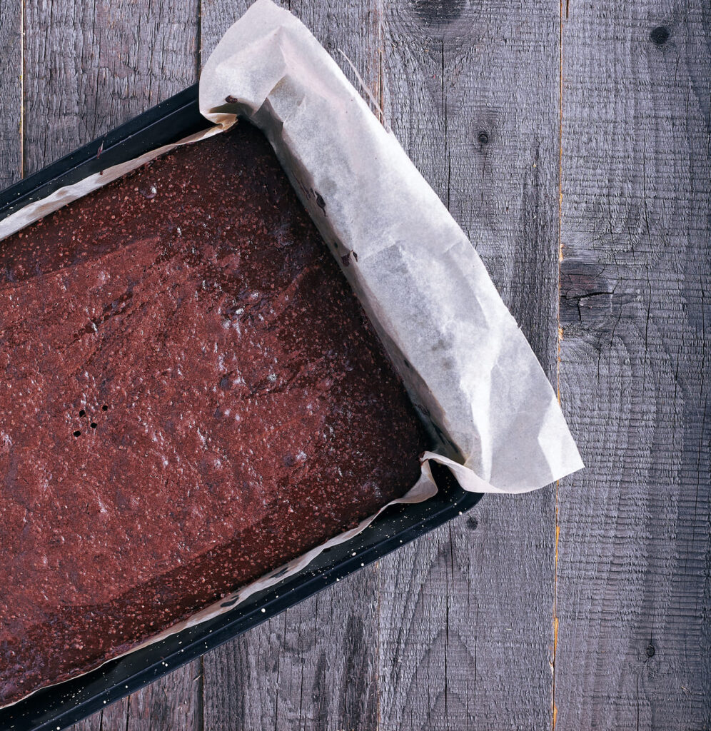 A tray of brownies being sliced with a hot knife into clean squares.