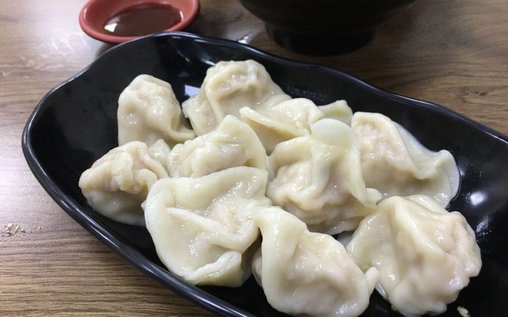 Plate of boiled dumplings with dipping sauce