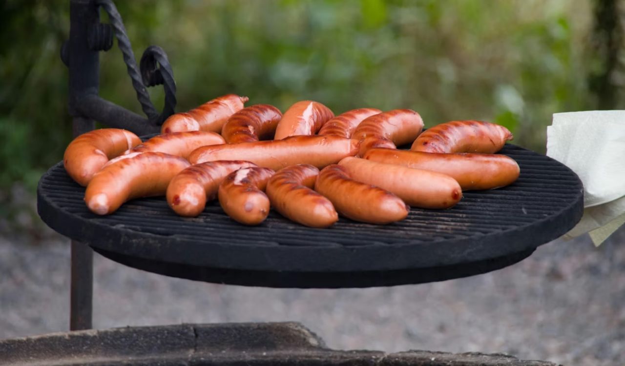 A bunch of hotdogs are on a grill