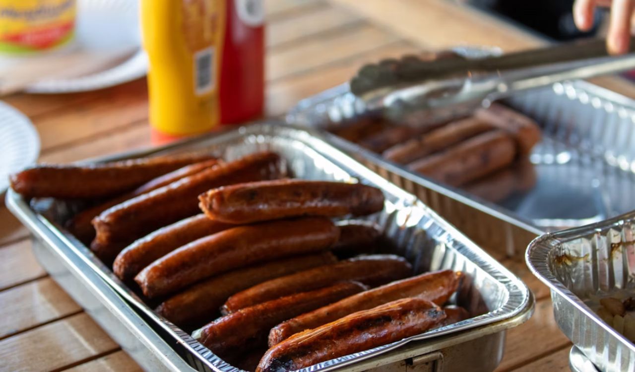 A couple of pans filled with hot dogs on top of a wooden table
