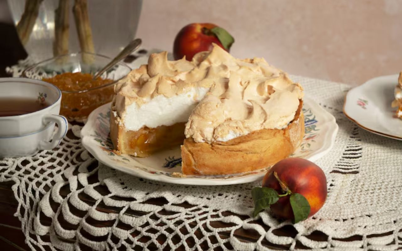 Peach meringue cake on a decorative plate with tea