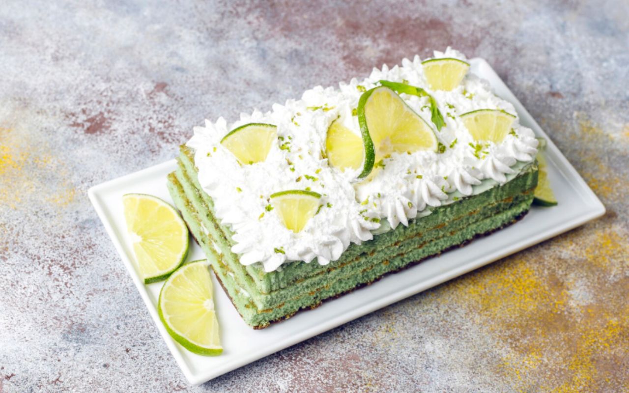 Avocado cake topped with whipped cream and lime slices