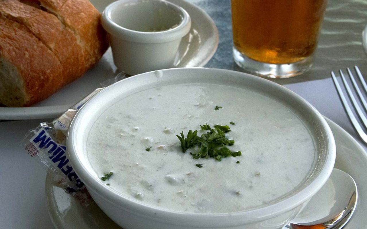 Bowl of creamy clam chowder with bread on the side
