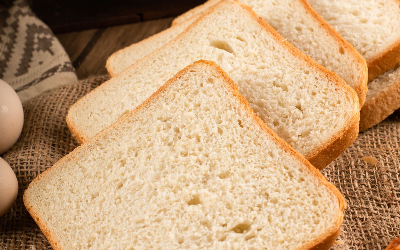 Sliced white bread on a rustic burlap surface