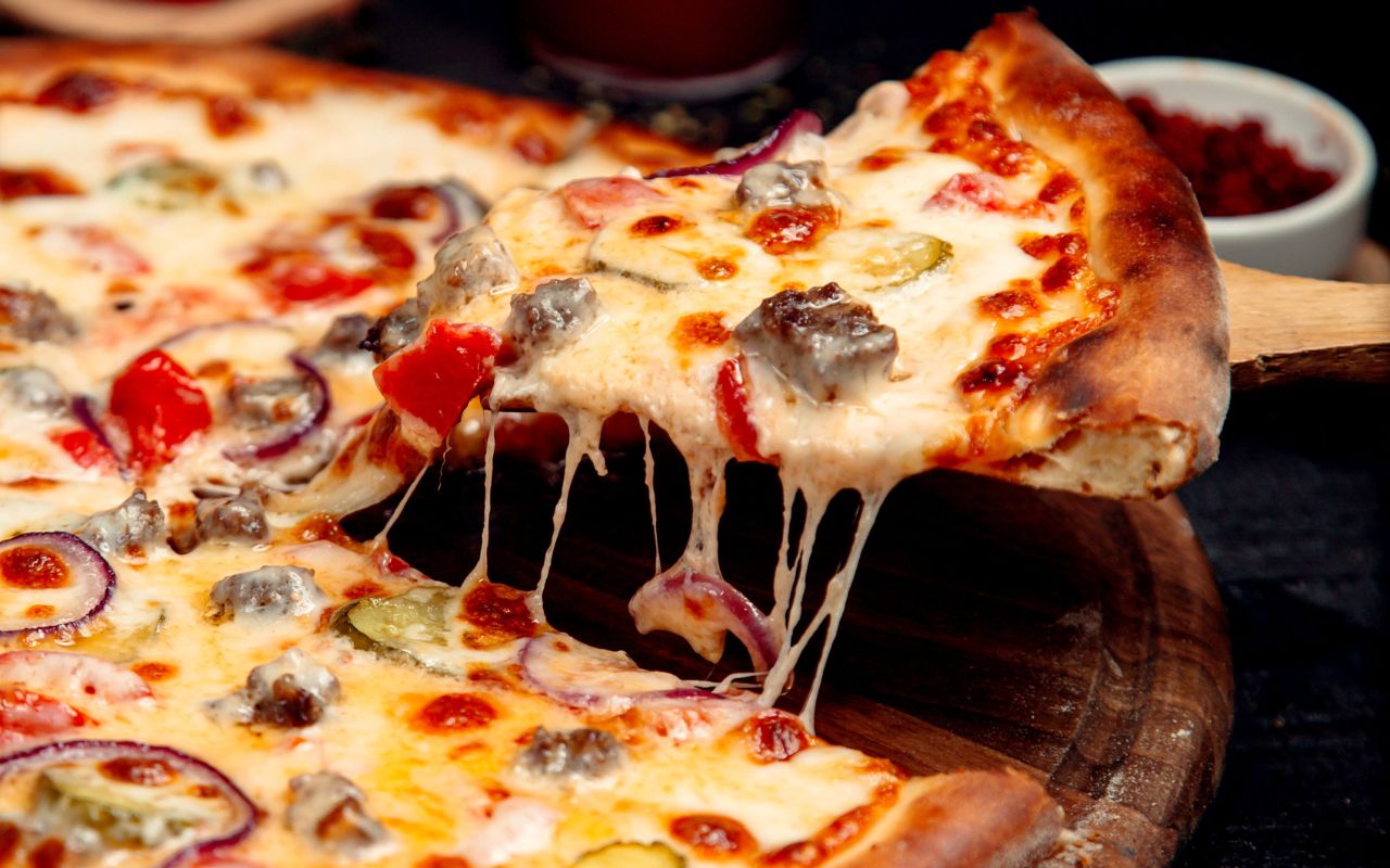 Cheesy pizza slice lifted with stretchy melted cheese