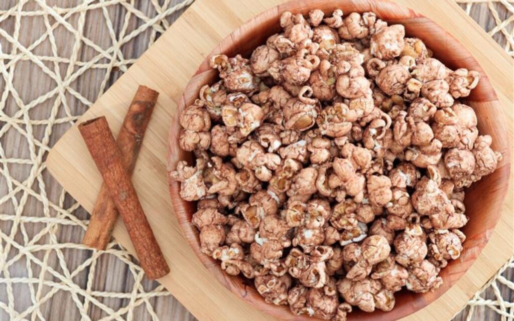 Bowl of cinnamon-coated popcorn with cinnamon sticks