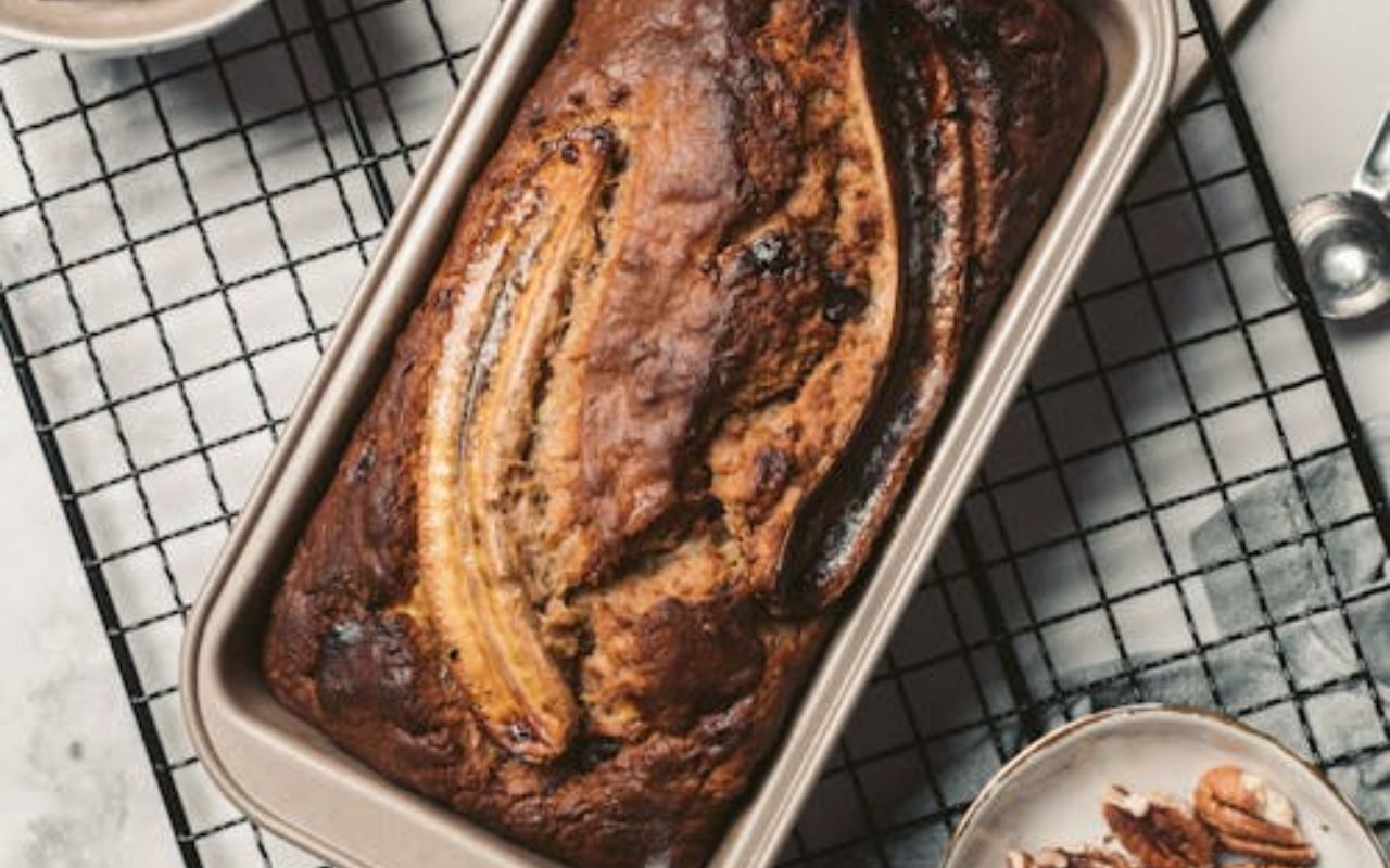 Banana bread loaf topped with split bananas in a baking pan