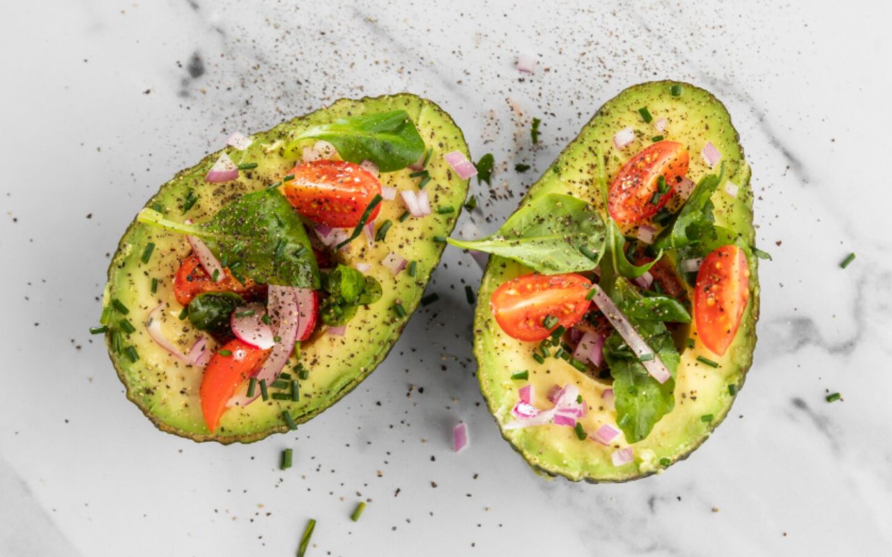 Flat lay delicious healthy salad in avocado composition