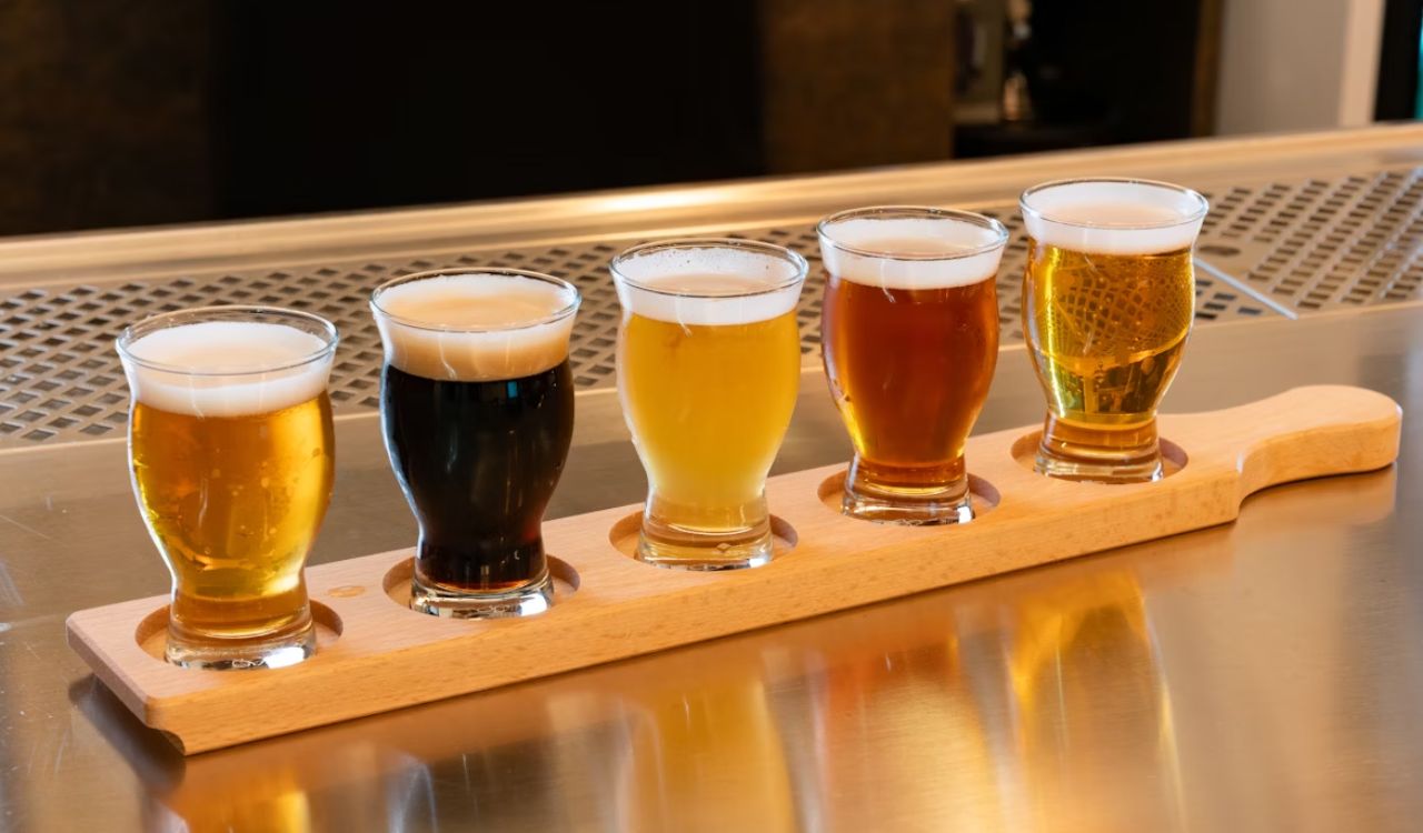 A row of beer glasses sitting on top of a wooden tray