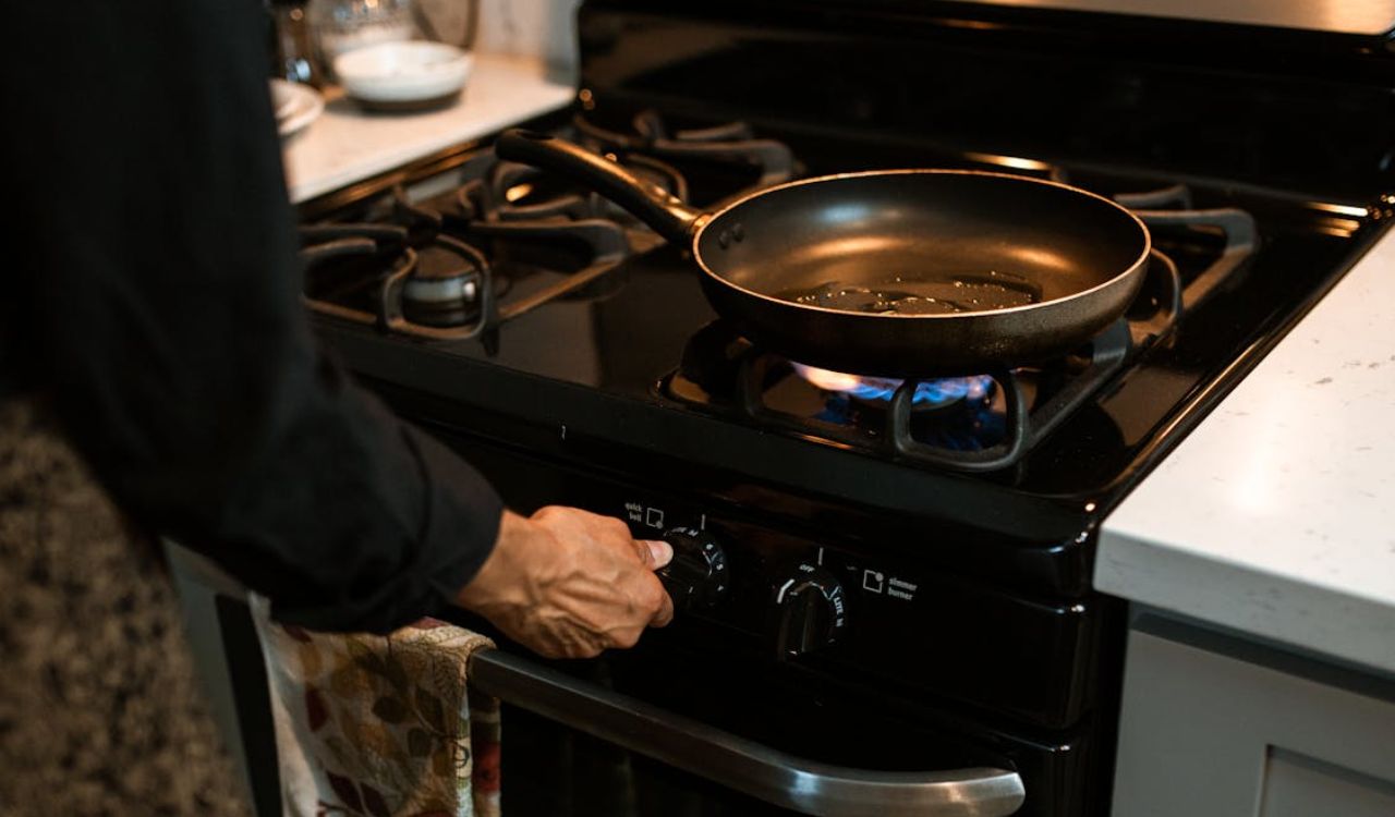 Crop faceless woman adjusting rotary switch of stove