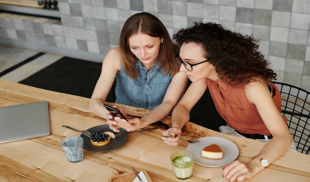 Women Eating Cakes and Looking at a Cellphone