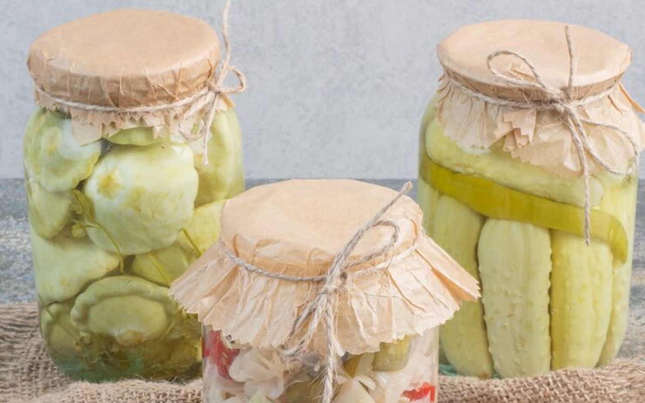 Glass jars of pickled vegetables with paper covers tied with string