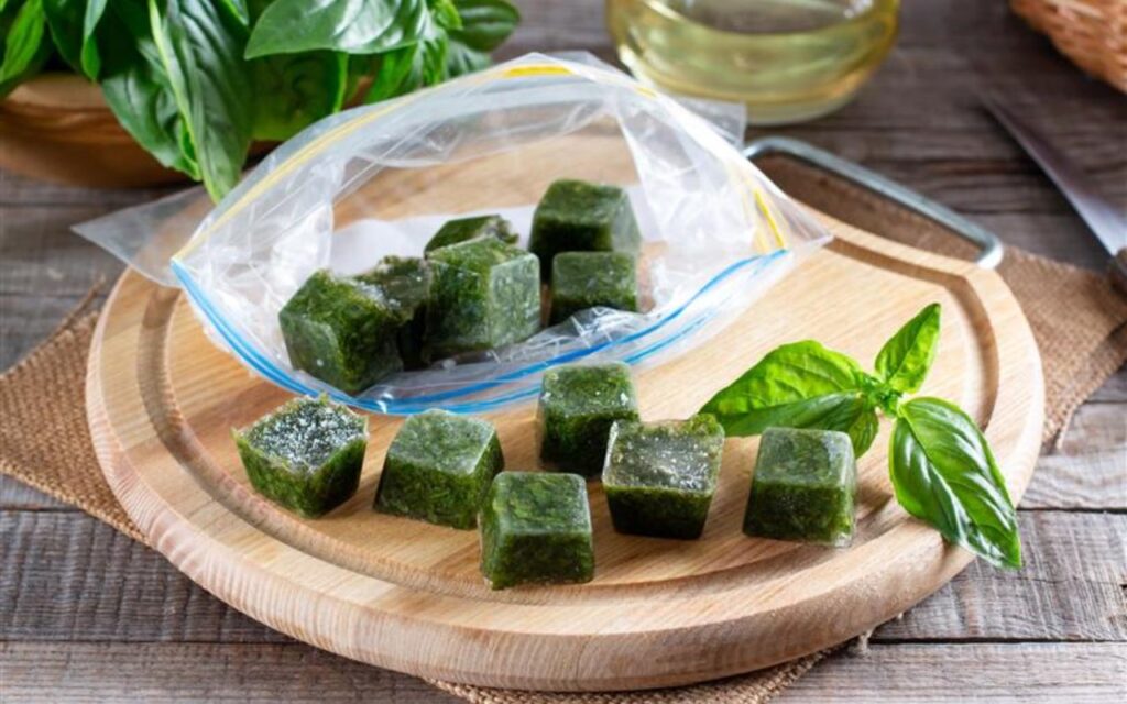 Frozen basil cubes in a resealable bag on a wooden board